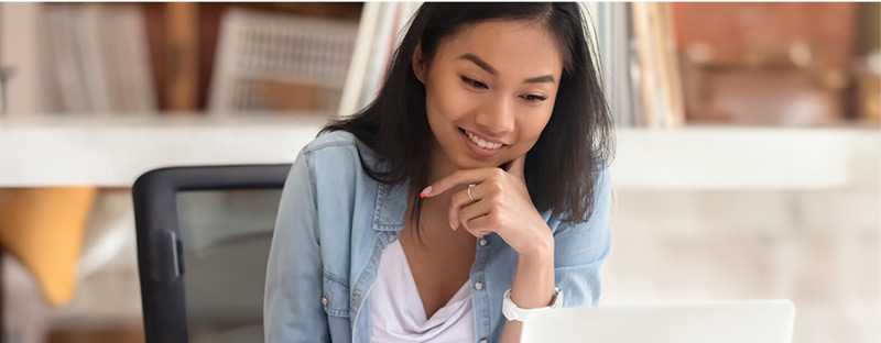 A smiling student working on a computer to get their financial aid.