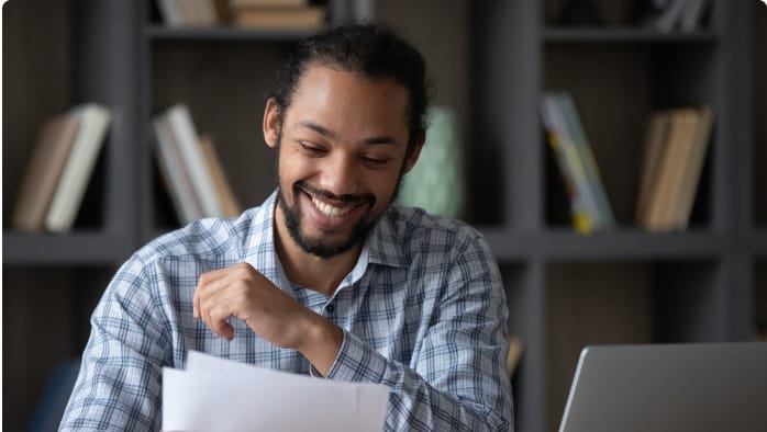 A man smiles as he reviews his grade on an English paper. 