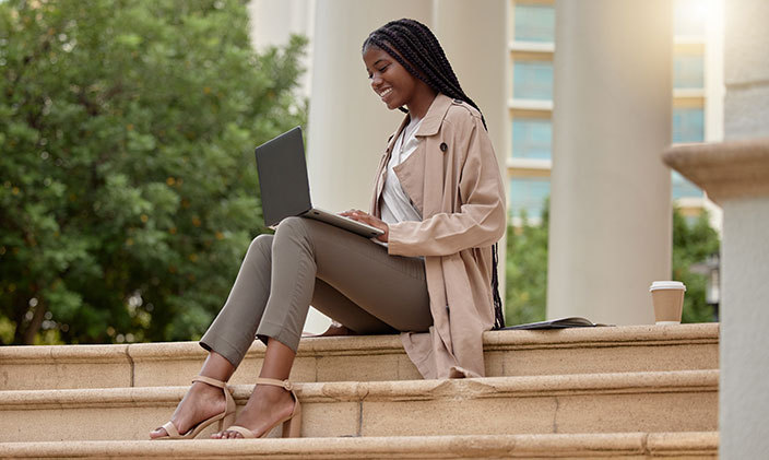 Young Black woman sitting on steps reading a textbook in her lap